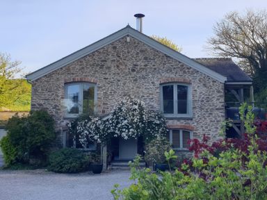 A stone house with windows and plants at Kerslake House in Crafthole