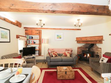 A living room with sofas a wooden chest coffee table a fireplace and a television at Honey Bee Cottage in Staintondale