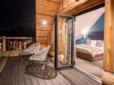 A bedroom with a bed and chairs on a balcony at The Lookout in Addingham