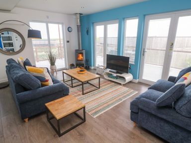 A living room with a sofa, coffee table and television at Pentewan - 67, Portreath