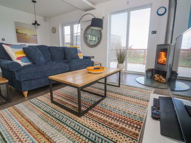 A living room with a sofa, coffee table, and fireplace at Pentewan - 67, Portreath