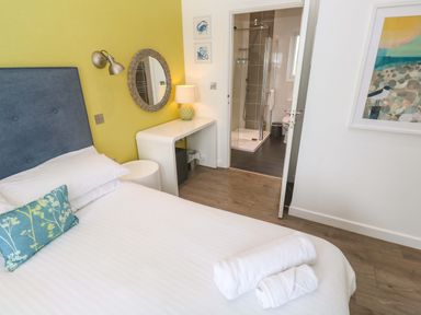 A bedroom with a bed and a bathroom doorway at Pentewan - 67 Portreath