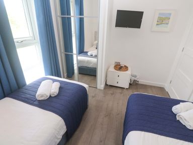 A bedroom with two beds, towels, a television and a mirror at Pentewan - 67 Portreath