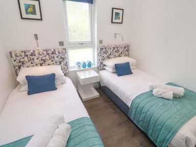 A bedroom with two beds and a bedside table at Pentewan - 67 Portreath