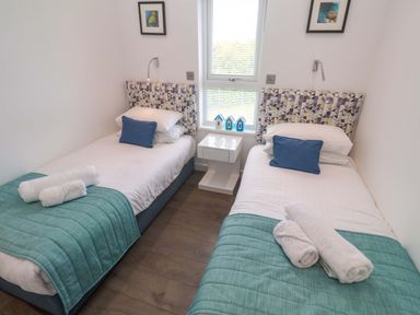 A bedroom with two single beds and a bedside table at Pentewan - 67, Portreath