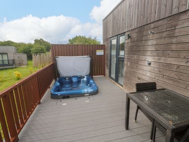 An outdoor area with a hot tub and a table at Pentewan - 67 in Portreath