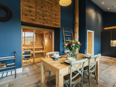 A dining room with a table and chairs next to a sauna at The Farmhouse in Addingham