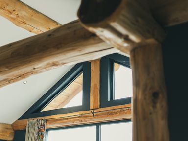 A living room with wooden beams and triangular windows at The Farmhouse in Addingham