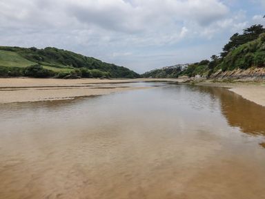 A river with sandbanks and green hills at No. 4 Fistral, Newquay