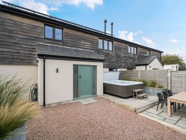 An outdoor area with a hot tub and seating at Bell House in Llanfechell