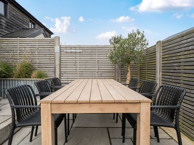 An outdoor dining area with a wooden table and black chairs at Bell House in Llanfechell