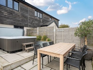 An outdoor area with a hot tub and dining table at Bell House in Llanfechell