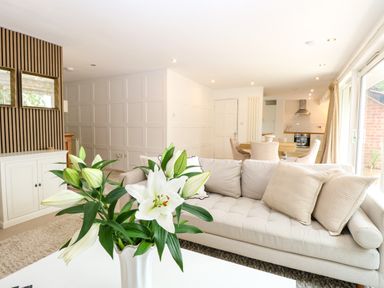 A living room with a sofa and vase of flowers at Three Ways in South Lopham near Garboldisham