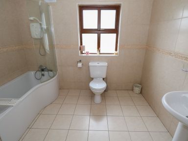 A bathroom with a bathtub, toilet, and sink at Tigh Marie