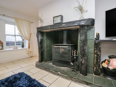 A living room with a fireplace and television at Newlands Fell House in Newlands near Keswick
