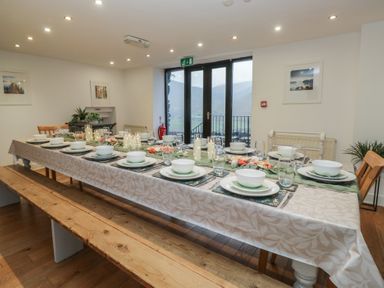 A dining room with a long table set for a meal at Newlands Fell House in Newlands near Keswick