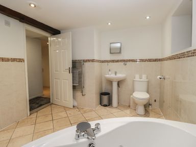 A bathroom with a bath tub, sink, and toilet at Newlands Fell House near Keswick