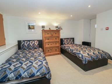 A bedroom with two beds and a wardrobe at Newlands Fell House in Newlands near Keswick