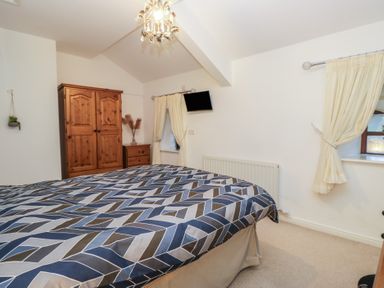 A bedroom with a bed, wooden wardrobe, and TV at Newlands Fell House in Newlands near Keswick