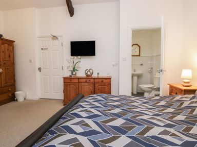 A bedroom with a bed, wardrobe, chest of drawers and bathroom at Newlands Fell House near Keswick