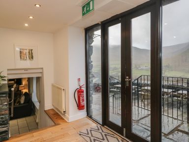 A hallway with sliding doors and wooden stairs at Newlands Fell House in Newlands near Keswick