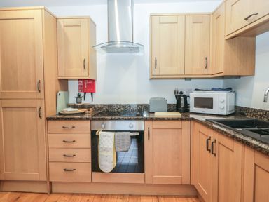 A kitchen with wooden cabinets and appliances at Newlands Cottage in Keswick