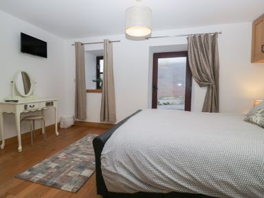 A bedroom with a bed and mirror at Newlands Cottage in Keswick