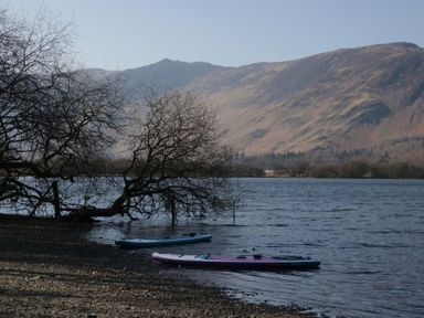 A lake with kayaks and mountains in the background at Newlands Cottage in Keswick