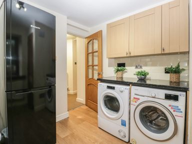 A laundry room with a refrigerator and washing machines at Birkbank Farm Cockermouth