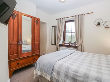 A bedroom with a bed and wardrobe at Birkbank Farm in Cockermouth