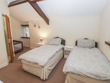 A bedroom with twin beds and a bedside table at Birkbank Farm in Cockermouth