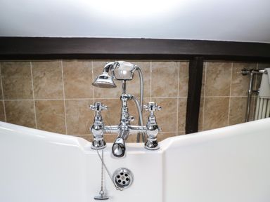 A bathtub with a chrome faucet and showerhead at Birkbank Farm in Cockermouth