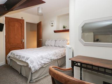 A bedroom with a bed and table at Birkbank Farm in Cockermouth