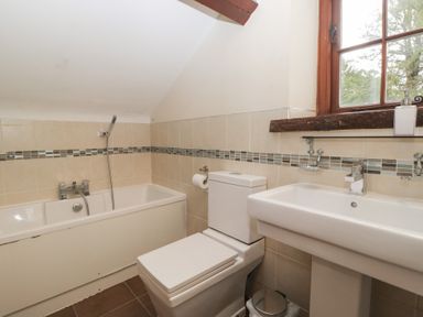 A bathroom with a bathtub, toilet, and sink at Birkbank Farm in Cockermouth
