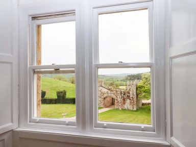 View from a window showing a stone wall and grass at Dowrich West Wing Apartment in Crediton