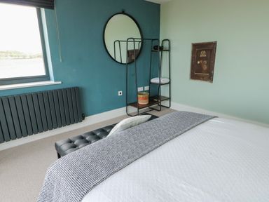 A bedroom with a bed and a mirror at Pengarnedd Amlwch