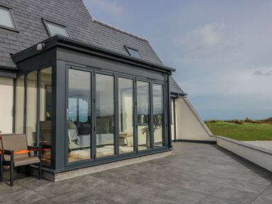 A conservatory with chairs and a sofa at Pengarnedd in Amlwch