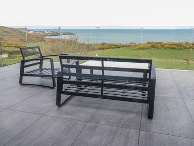 A patio with chairs and a table overlooking the sea at Pengarnedd Amlwch