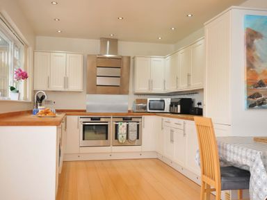 A kitchen with appliances and dining table at Porthmeor in Wadebridge