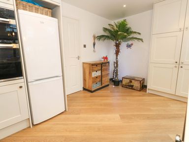 A kitchen with a refrigerator and wooden chest at Still Waters in Weymouth