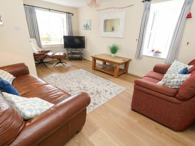 A living room with a sofa and television at Still Waters in Weymouth