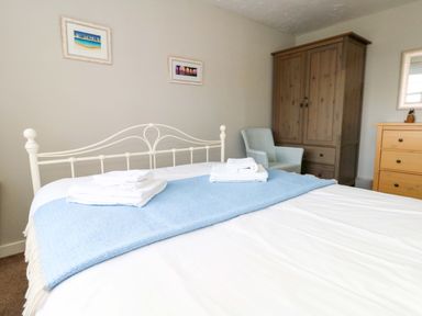 A bedroom featuring a bed, dresser, armoire, and chair at Still Waters in Weymouth
