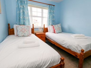 A bedroom with two single beds and a bedside table at Still Waters in Weymouth