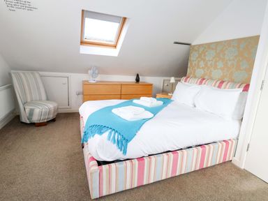 A bedroom with a bed and an armchair at Still Waters in Weymouth