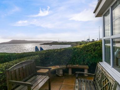 An outdoor area with benches and water view at Still Waters in Weymouth