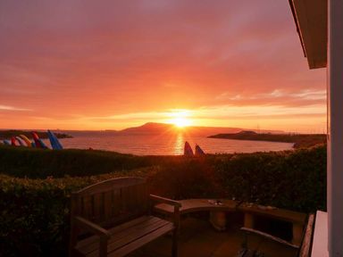 A sunset over the ocean with a bench and sailing boats at Still Waters in Weymouth