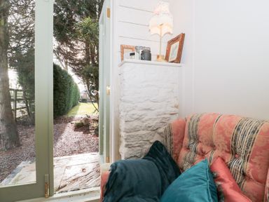 A seating area with a sofa and door leading to garden at Shades Farm Cabin Cirencester