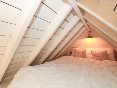 An attic with a bed and a light fixture at Shades Farm Cabin in Cirencester