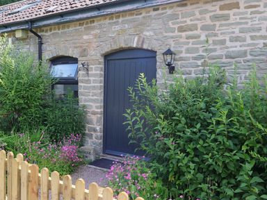 An entrance with plants and a wooden fence at Horse Gin in Parkend