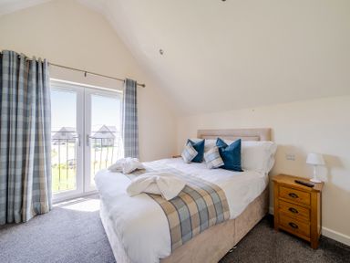 A bedroom with a bed and balcony door at James Ville Marina Lodge 7 Brigg